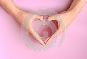 Female hands making heart on pink background. Love, friendship, peace concept. Valentine day, Birthday, Mothers Day.