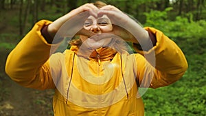 Female hands making sign Heart by fingers. Young Caucasian woman hiking and going camping in nature. Person with