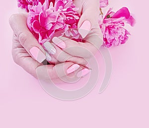 Female hands manicure style flower peony glamour on a pink background
