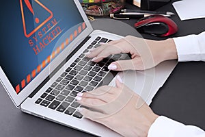 Female hands with manicure on laptop keyboard and warning on computer screen. system hacked