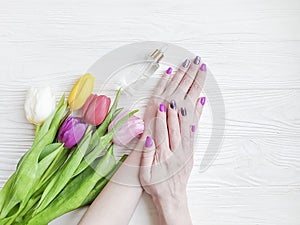 Female hands manicure, treatment cosmetic cream, tulip flower on wooden background