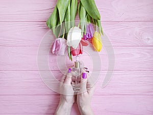Female hands manicure treatment health blossom cosmetic cream tulip flower on wooden background