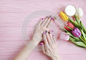 Female hands manicure treatment health relaxation blossom cosmetic cream tulip flower on wooden background