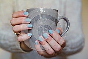 Female hands with manicured fingernails holding grey cup. Health, beauty, hands care