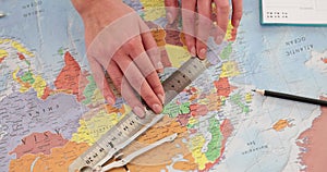 Female hands measure distances on world map using ruler and compass