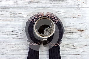 Female hands in mittens holding a cup of coffee, close-up