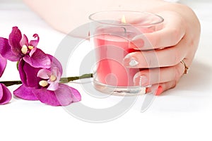 Female hands with orchid petals, candle and nail art