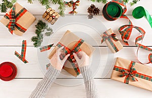 Female hands packaging xmas gifts at messy table background