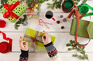 Female hands packaging xmas gifts at messy table background