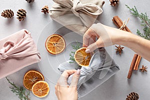 Female hands packing gifts in linen cloth. Furoshiki gifts.