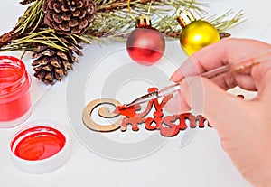 Female hands paint in red on the inscription Merry Christmas.Christmas decoration.