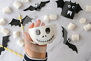 Female hands paint on white cup scary jacks face DIY for kids Halloween home activities Holiday art children craft