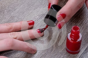 Female hands painting red nail varnish