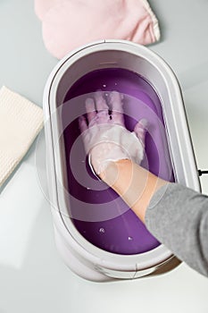 Female hands in a paraffin wax bowl