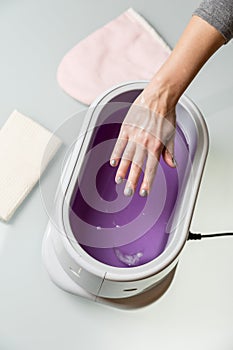 Female hands in a paraffin wax bowl photo