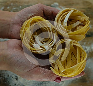 Female hands with pasta on wooden kitchen table  powdering by flour photo