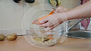 Female hands peeling raw carrots. Home kitchen.