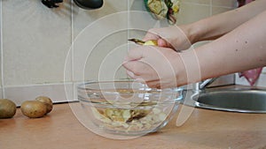 Female hands peeling raw potatoes. Home kitchen.