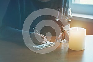 Female hands with pen and glass of wine writing