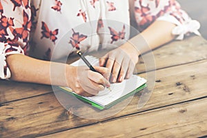 Female hands with pen writing on notebook