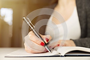 Female hands with pen writing on notebook. Diary, plans, journalist