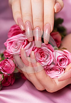 Female hands with pink nail design hold pink roses