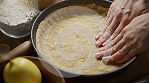 Female hands place the dough in a special baking dish. Cooking a delicious pie.