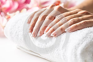 Female hands placed on a soft white towel ready for nails to be done in a manicure spa