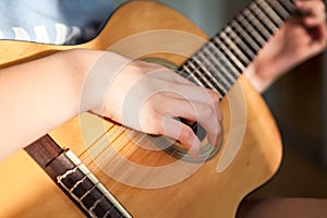 Female hands pluck the strings and fretboard of a yellow acoustic guitar, close up view
