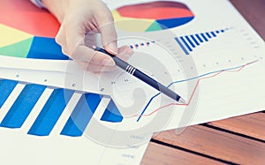 Female hands pointing with pen at business financial report graphic