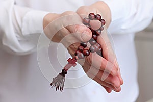 Female hands in pose of prayer with rosary beads