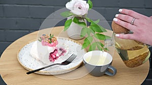 Female hands pour buckwheat tea into a cup from a glass teapot