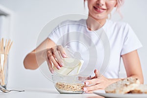 Female hands pouring milk into a cereal