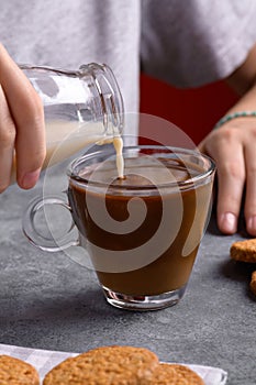 female hands pouring a vegan milk into a cup of coffee, make breakfast