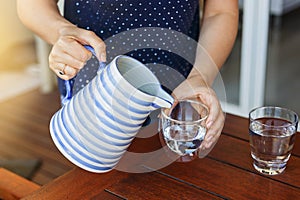 Female hands pouring water into glass