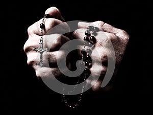 Female hands praying holding a rosary with Jesus Christ in the cross or Crucifix