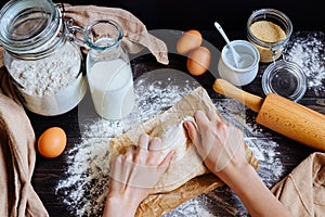Female hands preparing dough in the kitchen. Baking ingredients on the wooden table