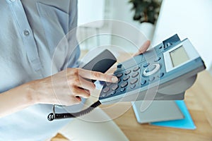 Female hands pressing a button on landline phone