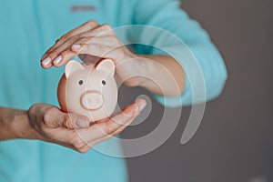 Female hands protect pink piggy bank, copy space. Concept of saving money or savings