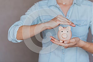 Female hands protect pink piggy bank, copy space. Concept of saving money or savings