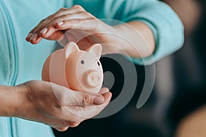 Female hands protect pink piggy bank, copy space. Concept of saving money or savings