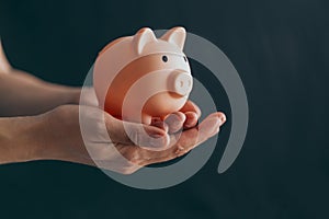 Female hands protect pink piggy bank, copy space. Concept of saving money or savings