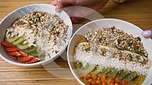 Female hands put fruit vegan bowls on wooden table in cafe