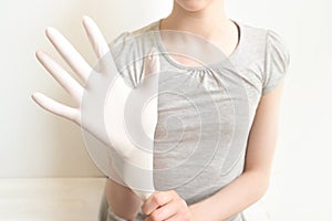 Female hands putting on latex gloves on white background