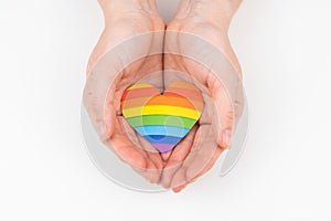 Female hands with rainbow paper heart isolated on white background.