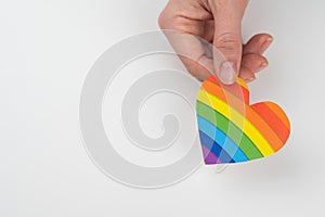 Female hands with rainbow paper heart isolated on white background. Copy space.
