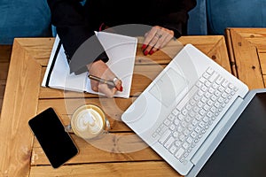 Female hands with red manicure on the background of a white laptop