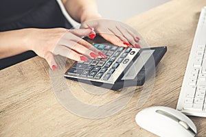 Female hands with red nails on a calculator keyboard