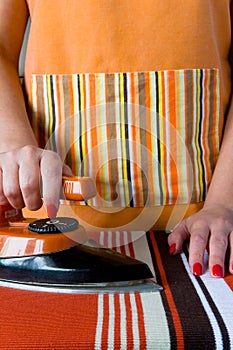 Female hands with red nails and an old electric iron.