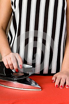 Female hands with red nails and an old electric iron.